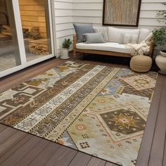 an outdoor area rug on a deck with a couch and potted plant in the background