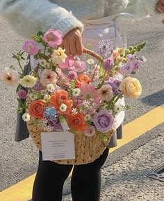 a woman holding a basket full of flowers on the side of the road while wearing tights