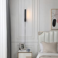 a white bed sitting next to a wall mounted light