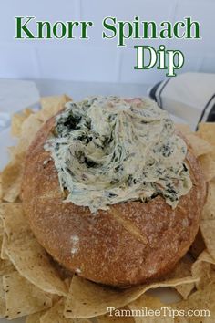 spinach dip in a bread bowl on top of tortilla chips with text overlay