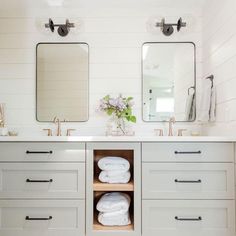 a bathroom with two sinks, mirrors and towels on the shelf in front of them