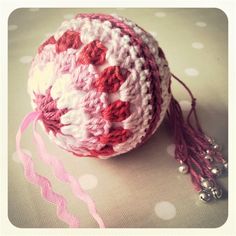 a crocheted ball with tassels and beads on it sitting on a table