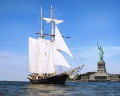 a sailboat sailing past the statue of liberty