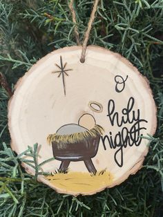 a wooden ornament with a nativity scene on it hanging from a tree