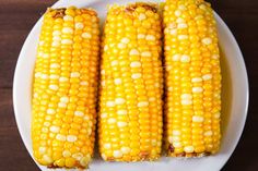 corn on the cob is sitting on a white plate and ready to be eaten