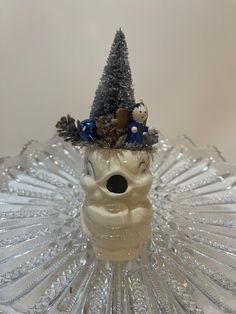 a glass figurine with a christmas tree on it's head in the shape of a human skull