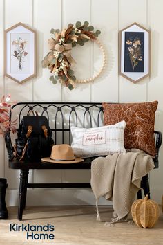 a bench that has some pillows on top of it and a wreath hanging above it