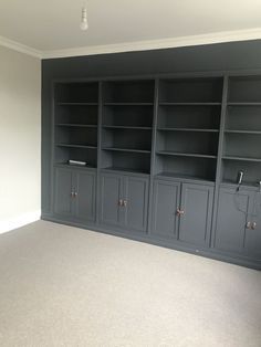 an empty room with gray bookcases and white carpeted flooring in the middle