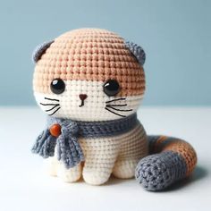 a small crocheted cat sitting on top of a white table next to a blue wall