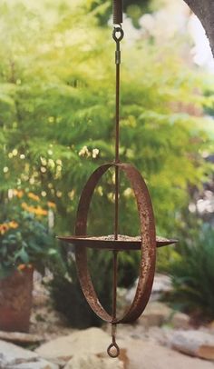 an old fashioned wind chime hanging from the side of a tree in a garden