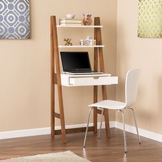 a laptop computer sitting on top of a white desk next to a wooden leaning shelf