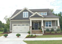 a gray house with white trim and two car garages on the front porch is shown