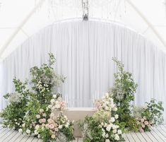 an arrangement of flowers and greenery in front of a white backdrop at a wedding