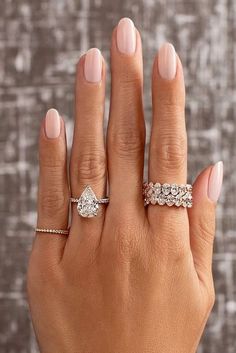 a woman's hand with three different rings on her fingers and one ring in the middle