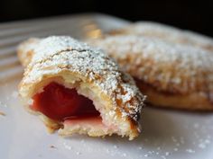 two pastries on a white plate with powdered sugar and jelly in the middle