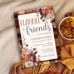 an open book on top of a blanket next to a bowl of dried flowers and leaves