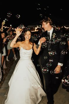 a bride and groom are walking through bubbles