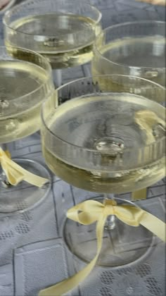 four wine glasses sitting on top of each other with yellow ribbons tied around the rims