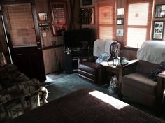 a living room filled with furniture and a flat screen tv on top of a wooden wall