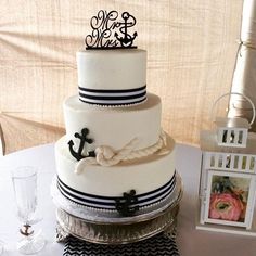 a white and black wedding cake with an anchor on top