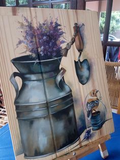 an easel with a painting of a watering can and flowers