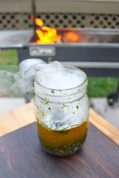 a jar filled with liquid sitting on top of a wooden table next to a fire pit