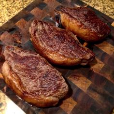 three pieces of meat sitting on top of a cutting board