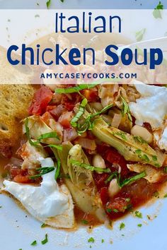 a white plate topped with chicken and vegetables next to bread on top of a table