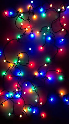 multicolored christmas lights hanging from the ceiling in front of a black background photo