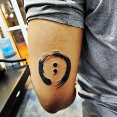 a man's arm with a tattoo on it that has a black circle in the middle