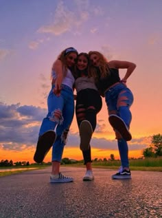 three young women are posing for a photo together on the street at sunset or dawn