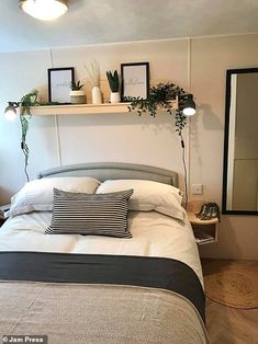 there is a bed with two plants on the headboard and one plant above it