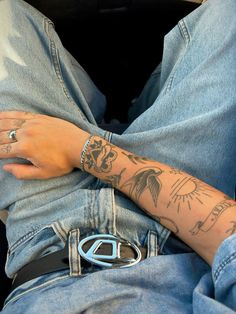 a person with tattoos on their arms and armbands sitting in a car seat