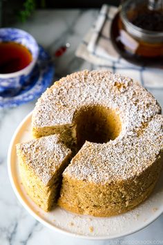 a cake sitting on top of a white plate next to a tea cup and saucer