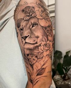 a man with a lion and flowers tattoo on his arm is holding a phone in front of him