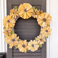 a wreath with yellow flowers is hanging on the front door, and it's made out of wood