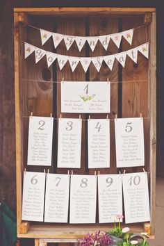 a wooden box filled with lots of cards and numbers on top of each other next to flowers