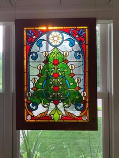 a stained glass window with a christmas tree hanging from it's side in front of a green lawn