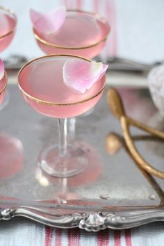 three glasses filled with pink liquid sitting on top of a silver tray