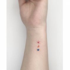 a person's arm with a small star and crescent tattoo on the left wrist