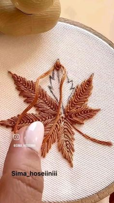 a person is stitching leaves on a piece of fabric with their thumbnails