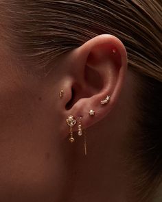 a woman wearing gold ear piercings with pearls on her ears and behind her ear