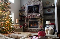 a living room with a christmas tree in the corner and a tv above the fireplace