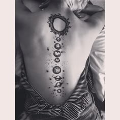 the back of a woman's body with phases and stars tattooed on her lower back