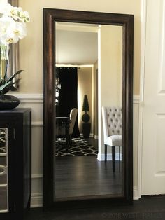 a large mirror sitting on the side of a wall next to a chair and table