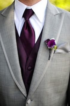 a man wearing a suit and tie with a purple flower in his lapel pocket