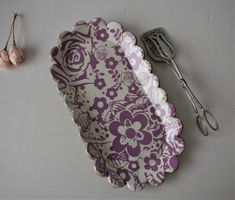 a purple and white plate with flowers on it next to some utensils,