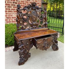 an ornate wooden bench sitting in front of a brick building