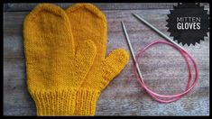 a pair of yellow knitted mittens next to a pair of pink knitting needles