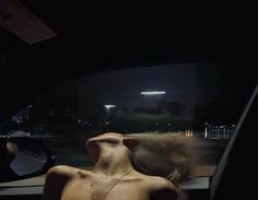 a naked woman sitting in the back seat of a car with her head turned to the side